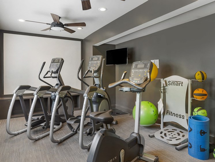 a gym with various exercise machines and a television